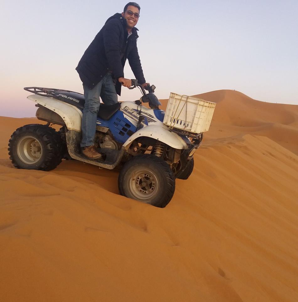 A photograph of Youssef Nomada riding a quad bike down a sand dune in Morocco