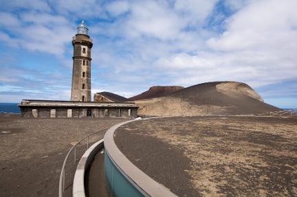 A photgraph of a lighthouse and scoria cone, Vulcão dos Capelinhos taken on GeoWorld Travel's geology of the Azores tour