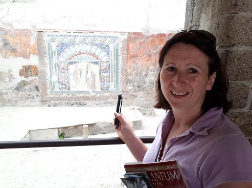 A photograph of archaeologist Abby Hunt pointing at a Roman picture on GeoWorld Travel's geology of Italy tour