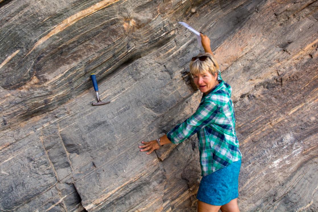 A photograph of geologist Nicole Grünert standing in front of metamorphic rock on GeoWorld Travel's geology of Namibia tour