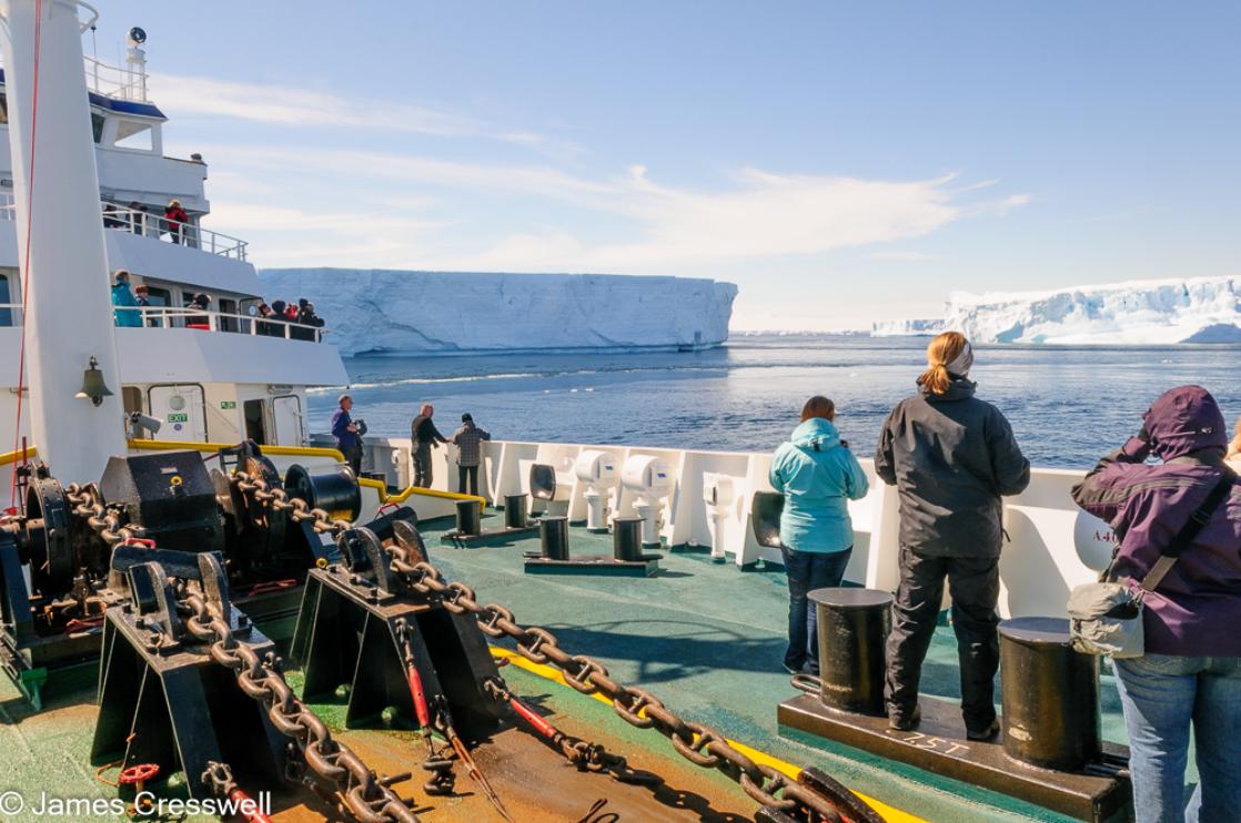 A photograph of the m/v Plancius steers through huge tabular icebergs in Antarctic Sound