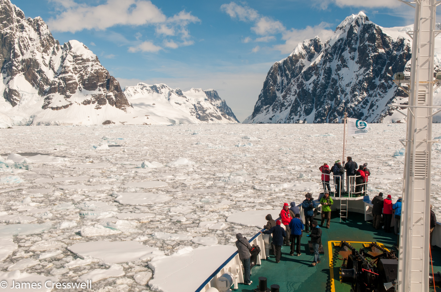 A photograph of a ship pushing through sea ice in the Lemaire Channel Antarctica on a PolarWorld Travel placed cruise