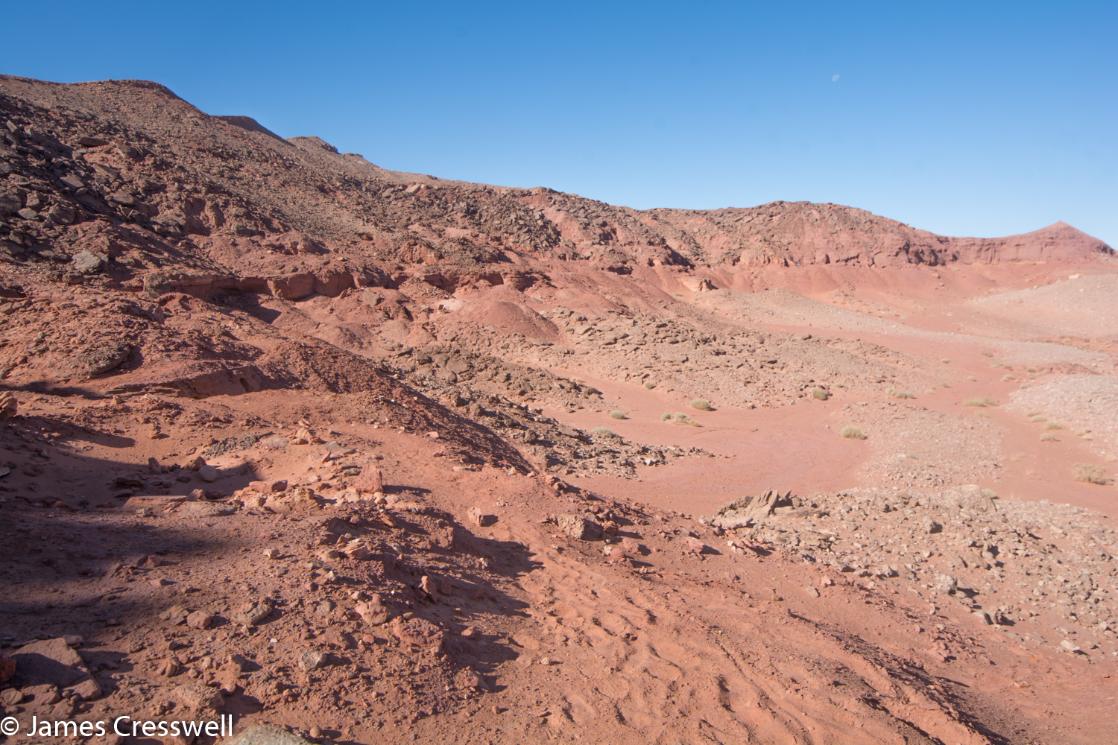 A photograph of fossil quarry working in red rock, the Kem Kem dinosaur beds in Morocco, taken on a GeoWorld Travel geology and fossil trip and holiday