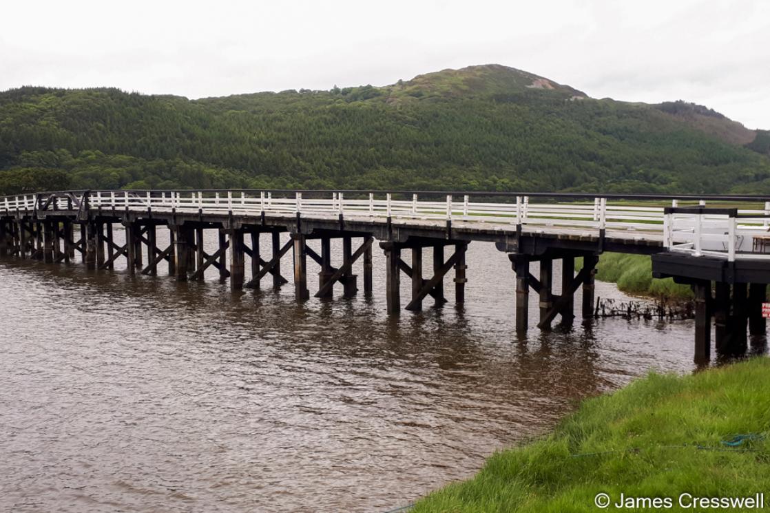 A photograph of Penmeanpool toll bridge and gold mine spoil heaps behind, taken on a GeoWorld Travel geology tour, trip and holiday of Wales