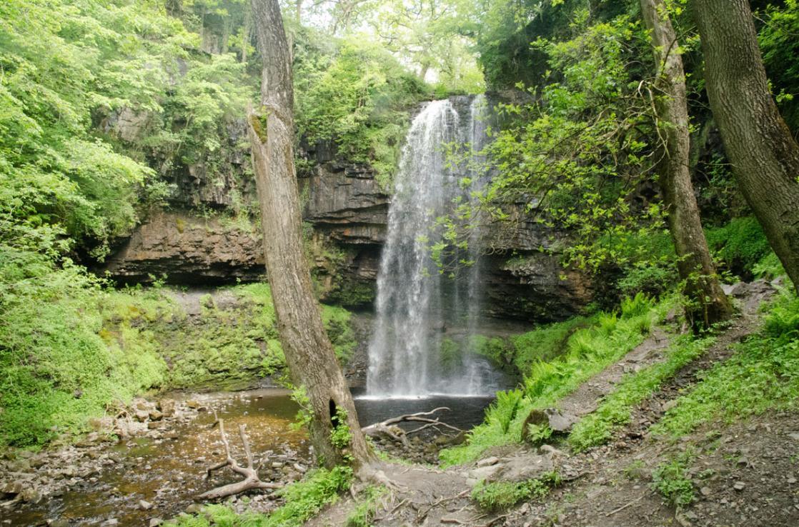 A photograph of Henrhyd waterfall flowing over the Farewell Rock, taken on a GeoWorld Travel Fforest Fawr Geopark geology day tour