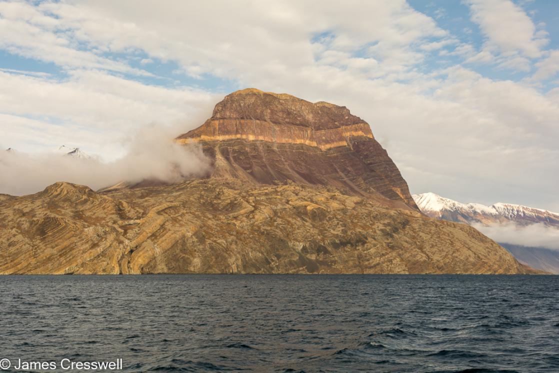 A photograph of Teufelschloss (Devil'sCastle) in Kejser Franz Josef Fjord, northeast Greenland. The sedimentary rocks layers are part of the Eleonore Bay Formation, taken on a PolarWorld Travel polar expedition cruise