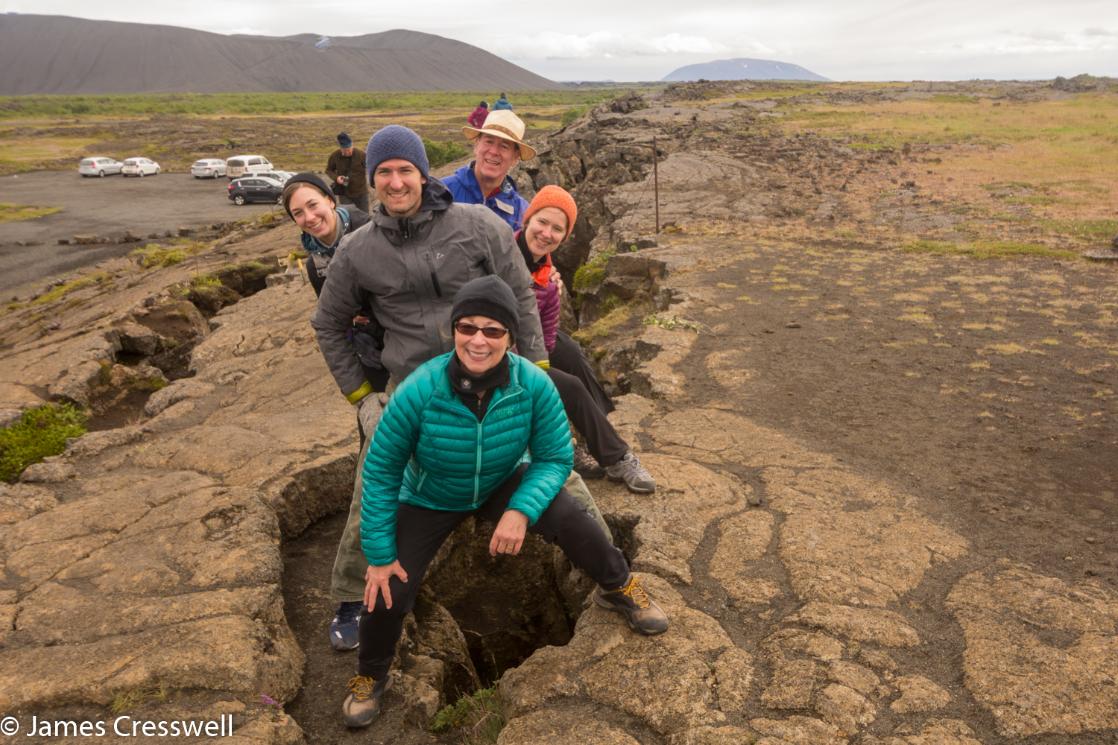 A photograph of five people straddling an extension fracture on a plate boundary, taken on a GeoWorld Travel geology holiday and volcano trip 