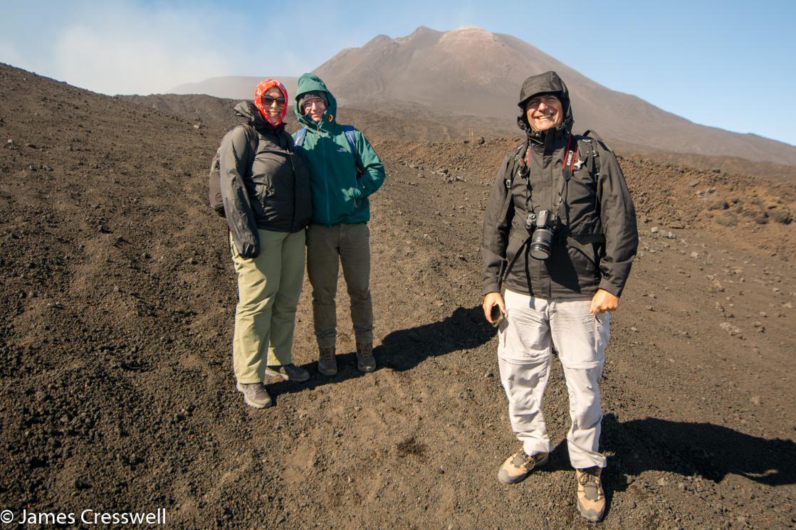 A photograph of three people with the summit cones of Etna volcano in the background, taken on a GeoWorld travel volcano trip and geology holiday