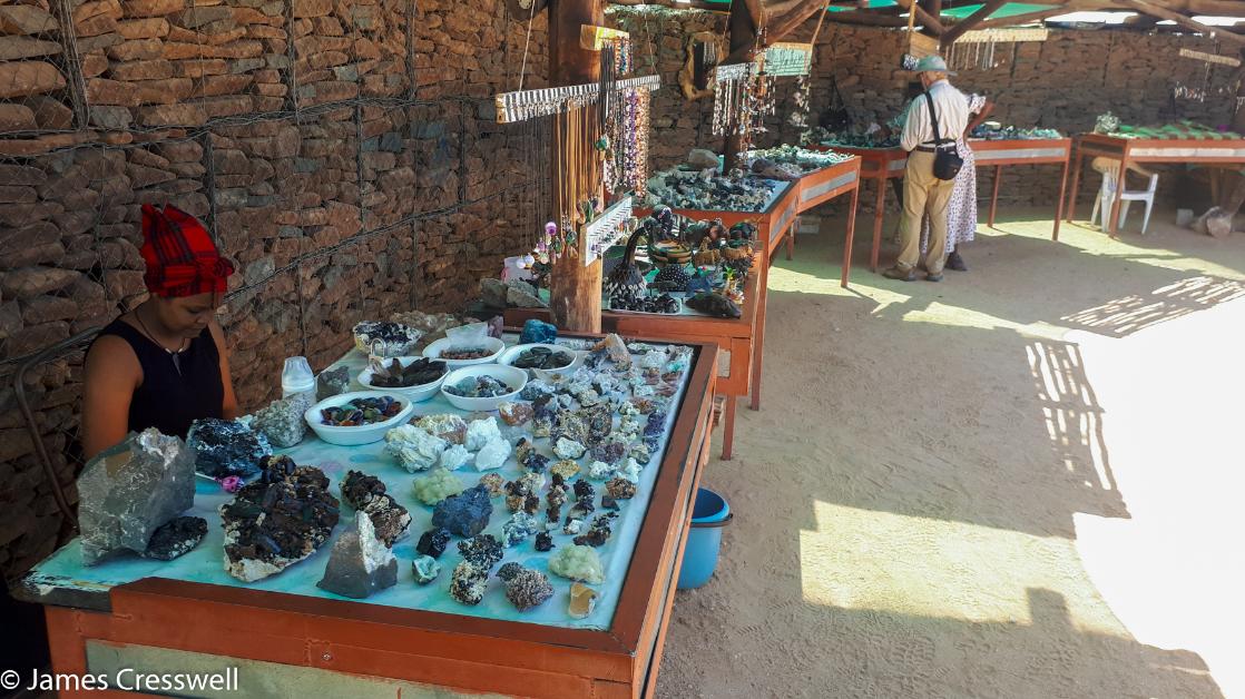 A photograph of 7 tables displaying mineral for sale at a mineral market in Namibia, taken on a GeoWorld Travel Namibia geology trip, tour and holiday