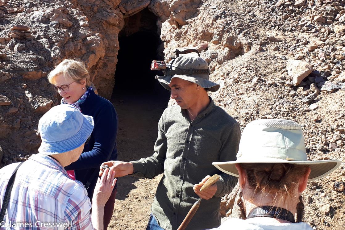 A photograph of a man showing a mineral at the entrance to a mineral mine, taken on a GeoWorld Travel mining trip on a Morocco geology tour and holiday