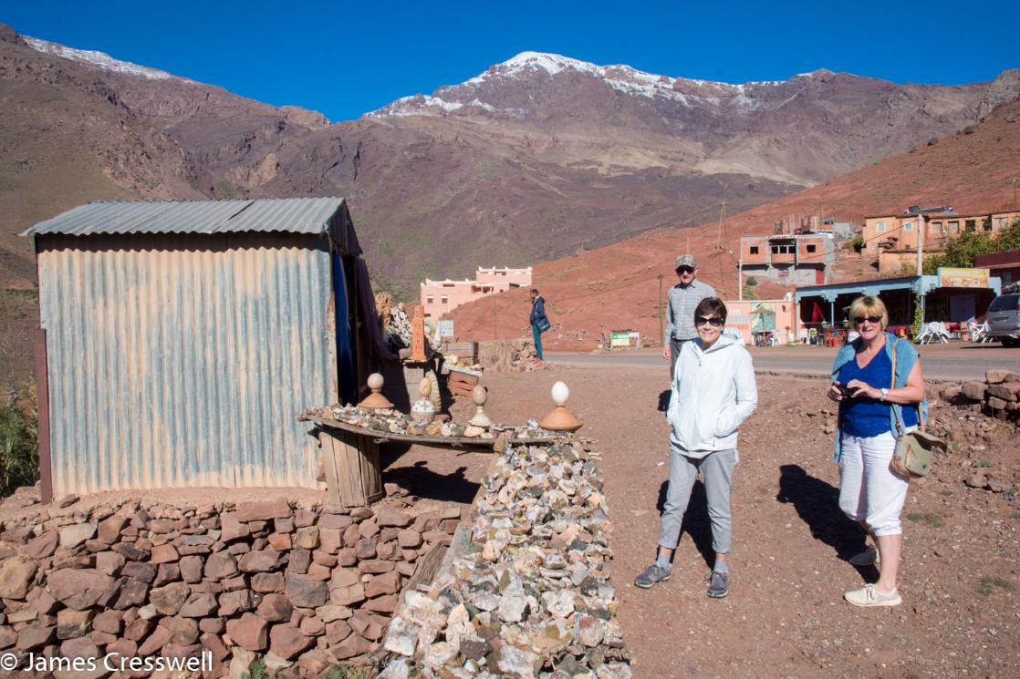 A photograph of two people standing in front on snow topped mountains, the High Atlas, taken on a GeoWorld Travel fossil geology trip, tour and holiday