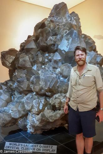 A photograph of James Cresswell with the world's largest quartz crystal in the in the Kristall Gallerie in Swakopmund, on a GeoWorld Travel Namibia geology tour, trip and holiday