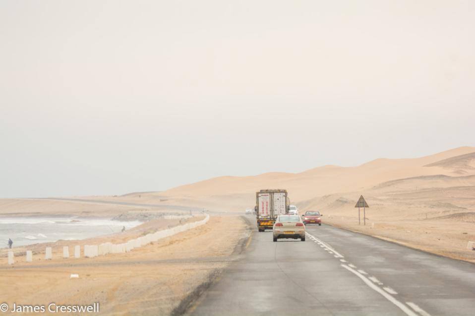 A photograph of a foggy coastal road in desert dunes,taken on a GeoWorld Travel Namibia geology trip, tour and holiday
