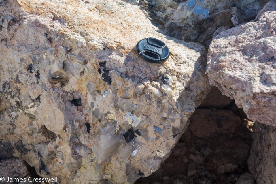 A photograph of a pegmatite vein with large tourmaline, quartz and mica crystals, taken on a GeoWorld Travel Namibia geology trip, tour and holiday