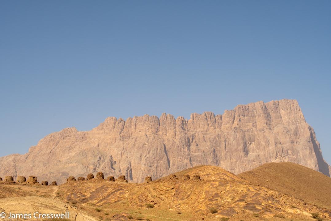A photograph of Jebel Misht mountain and the Al Ayn beehive tombs World Heritage Site, taken on a GeoWorld Travel Oman geology trip, tour and holiday