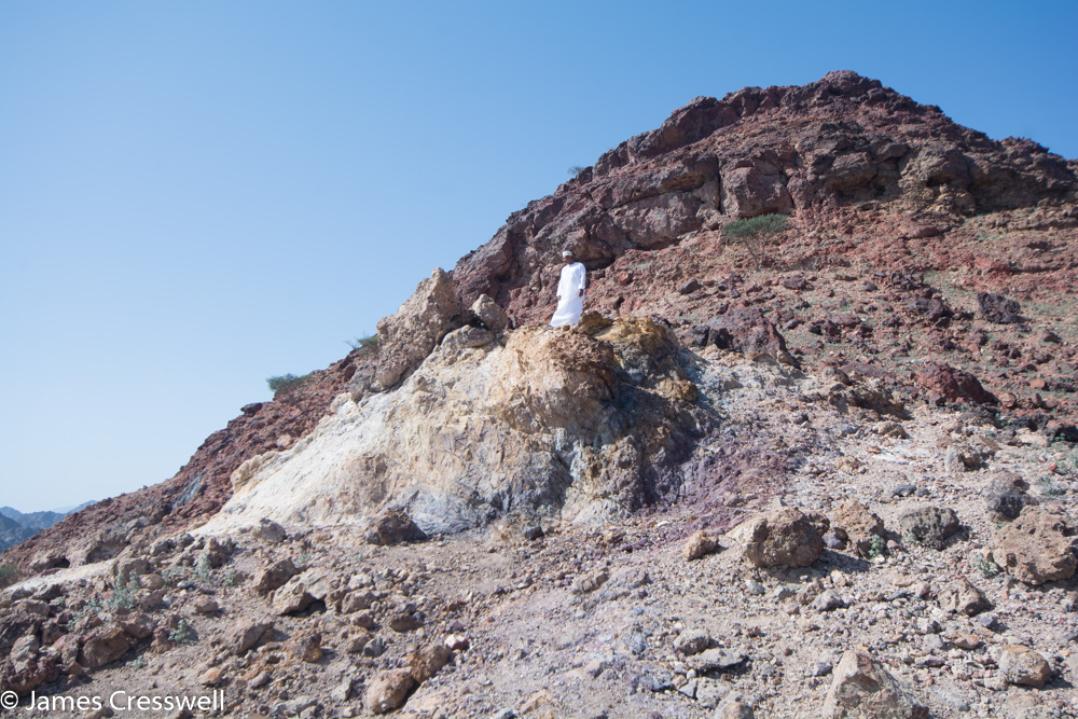 A photograph of a man standing on a fossilized Black Smoker, taken on a GeoWorld Travel Oman geology trip, tour and holiday