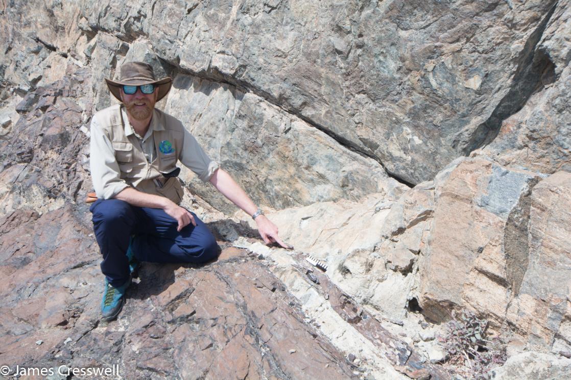 A photograph of James Cresswell pointing to the Moho in the Semail Ophiolite, taken on a GeoWorld Travel Oman geology trip, tour and holiday