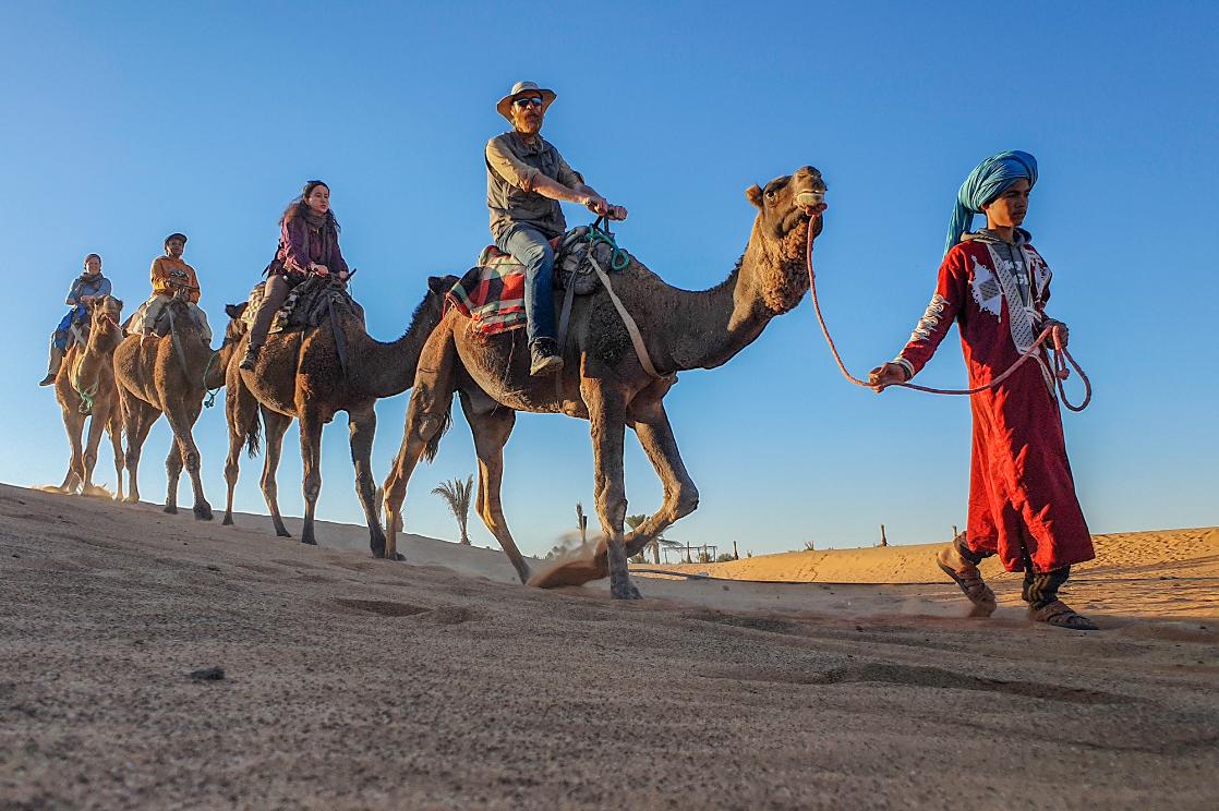 A photo of a GeoWorld Travel group riding camels in Morocco