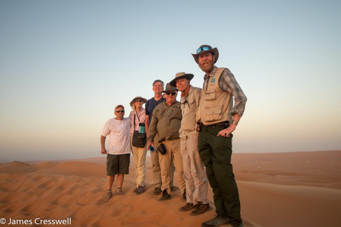 A photograph of six people including James Cresswell standing on top of a sand dune in the Wahiba Sands, taken on a GeoWorld Travel Oman geology trip, tour and holiday
