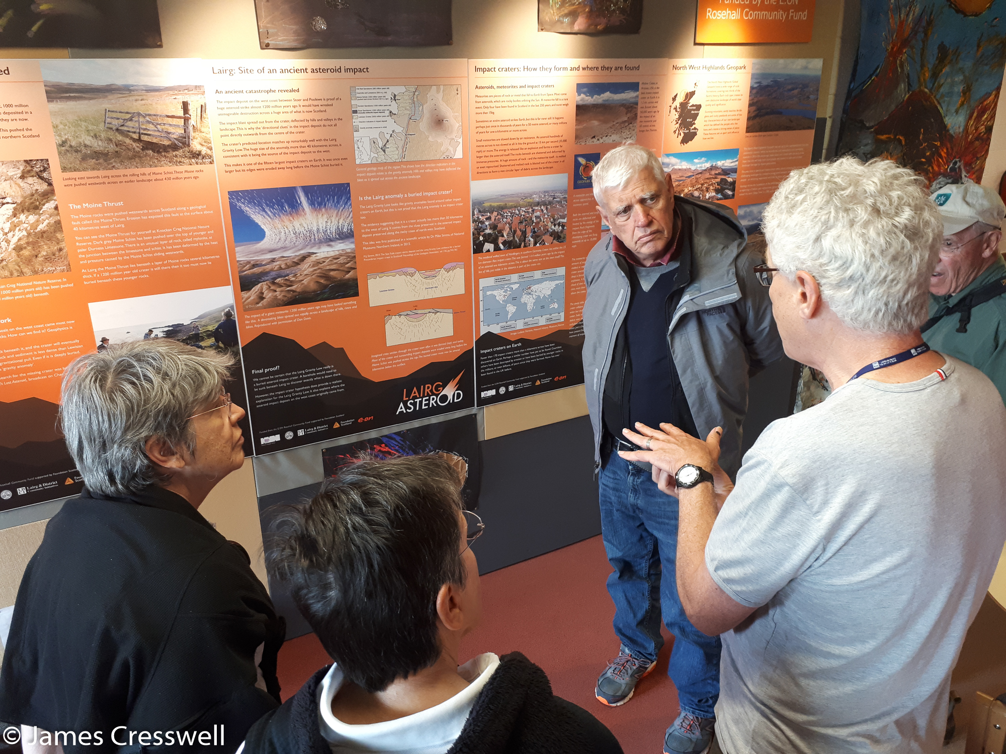 A photograph of a group of people in front of Lairg asteroid information boards at the Ferrycroft Visitor Centre, taken on a GeoWorld Travel Scotland geology trip, tour and holiday