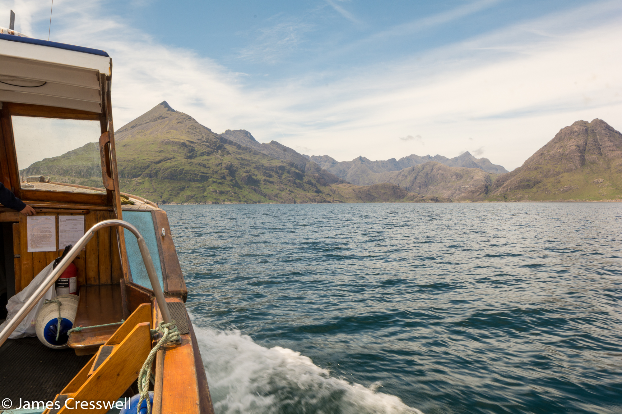 A photograph with part of a boat in the foreground of the Black Cuillin mountains on the Isle of Skye, taken on a GeoWorld Travel Scotland geology trip, tour and holiday